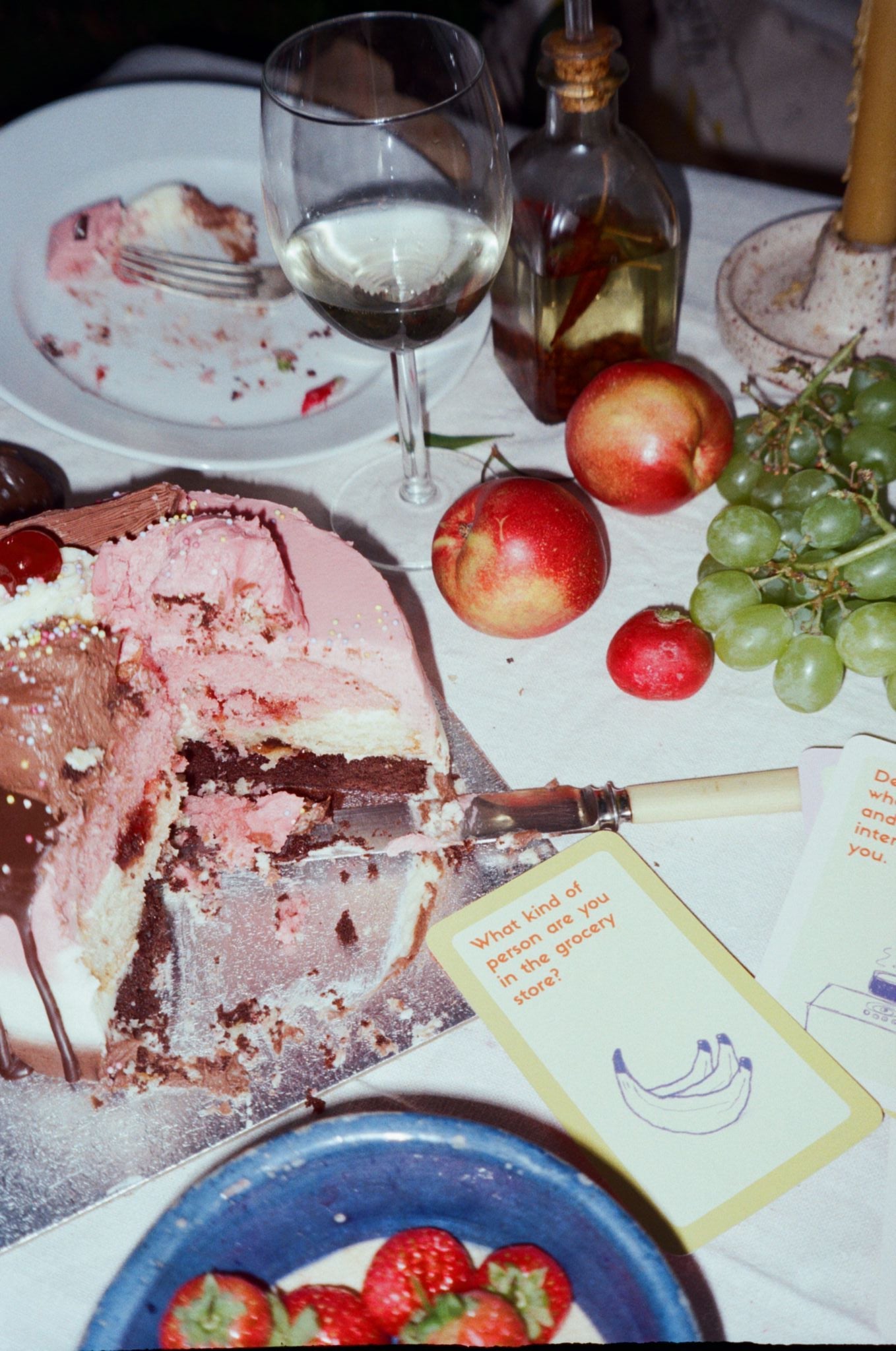 Dessert scene with cake, fruit, and wine on a table