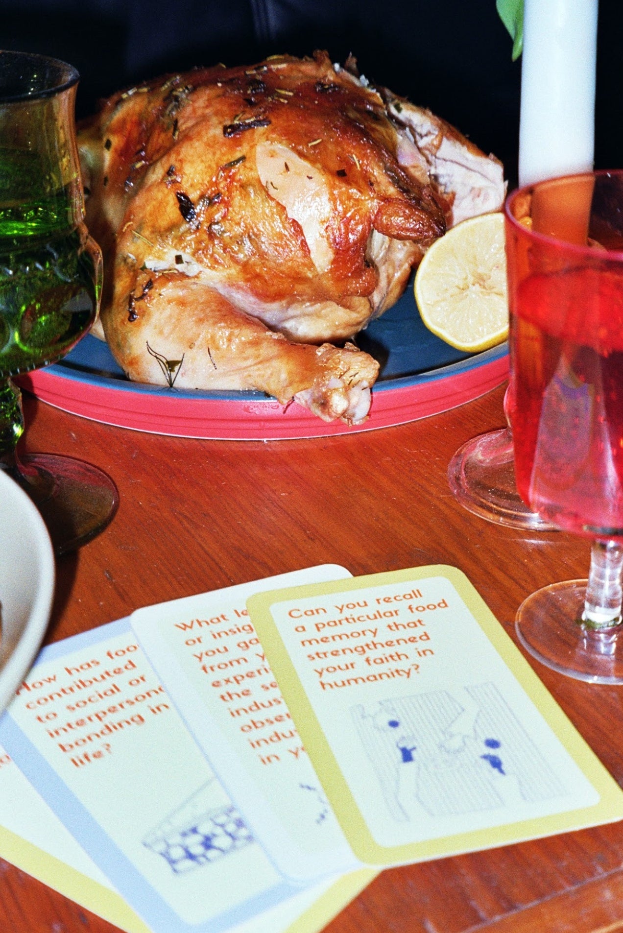 Roasted chicken on a plate with a glass of red wine and a menu on a wooden table.
